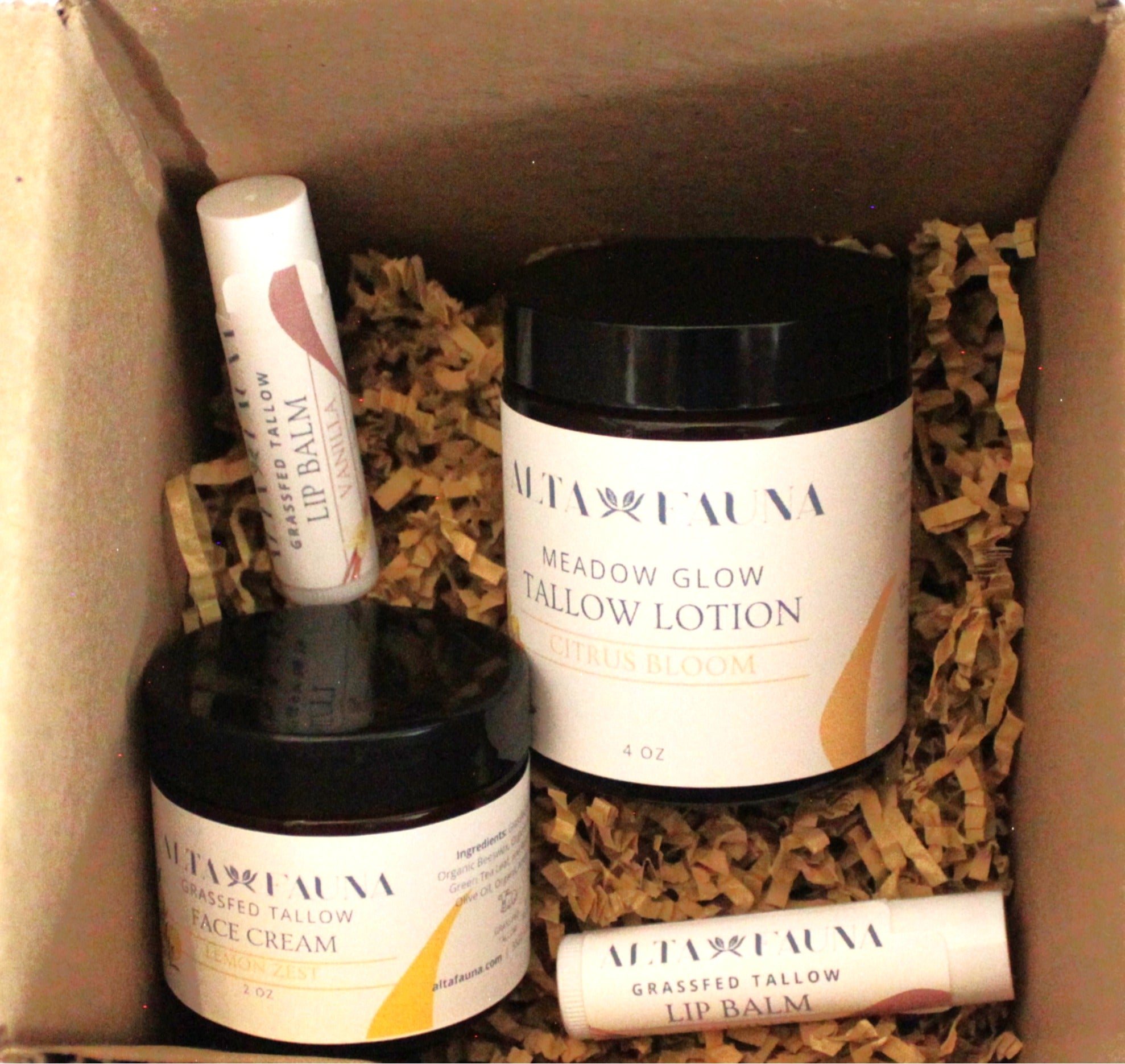 A curated set of Alta Fauna products in citrus scents. Pictured are Tallow Lotion in Citrus Bloom, Lemon Zest Face Cream and two lip balms shown in a box with packing materials.