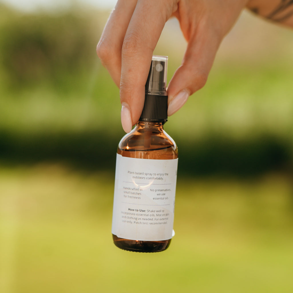 Alta Fauna Bug Guard being held by a hand showing the back of the amber bottle with directions and information.