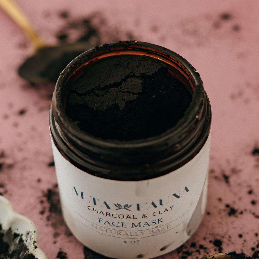 Alta Fauna charcoal and clay face mask in amber, glass jar with the lid off on a pink background.