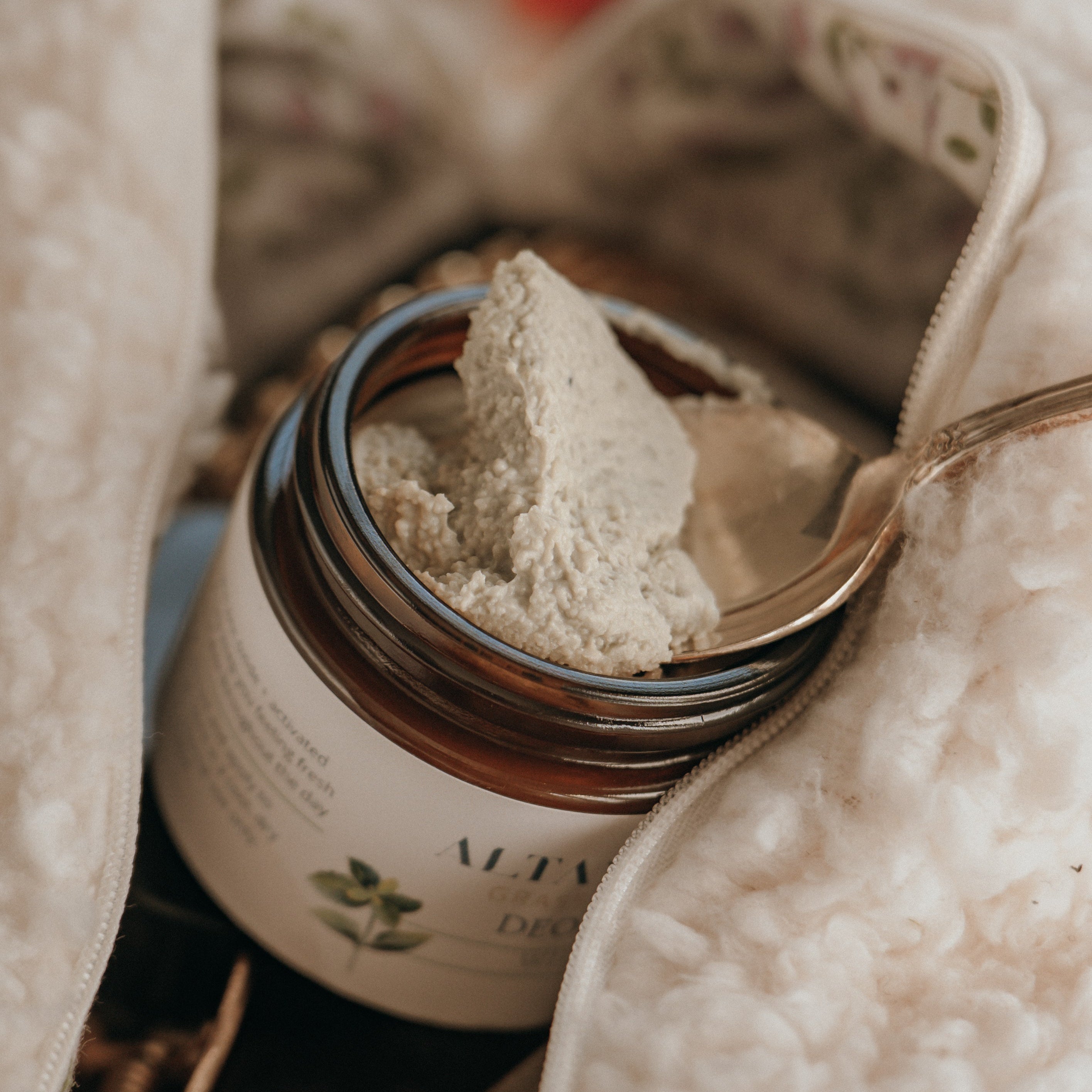 Close‑up of Alta Fauna aluminum‑free tallow deodorant. Amber glass jar with a spoon shows the deodorant outside of the jar. 