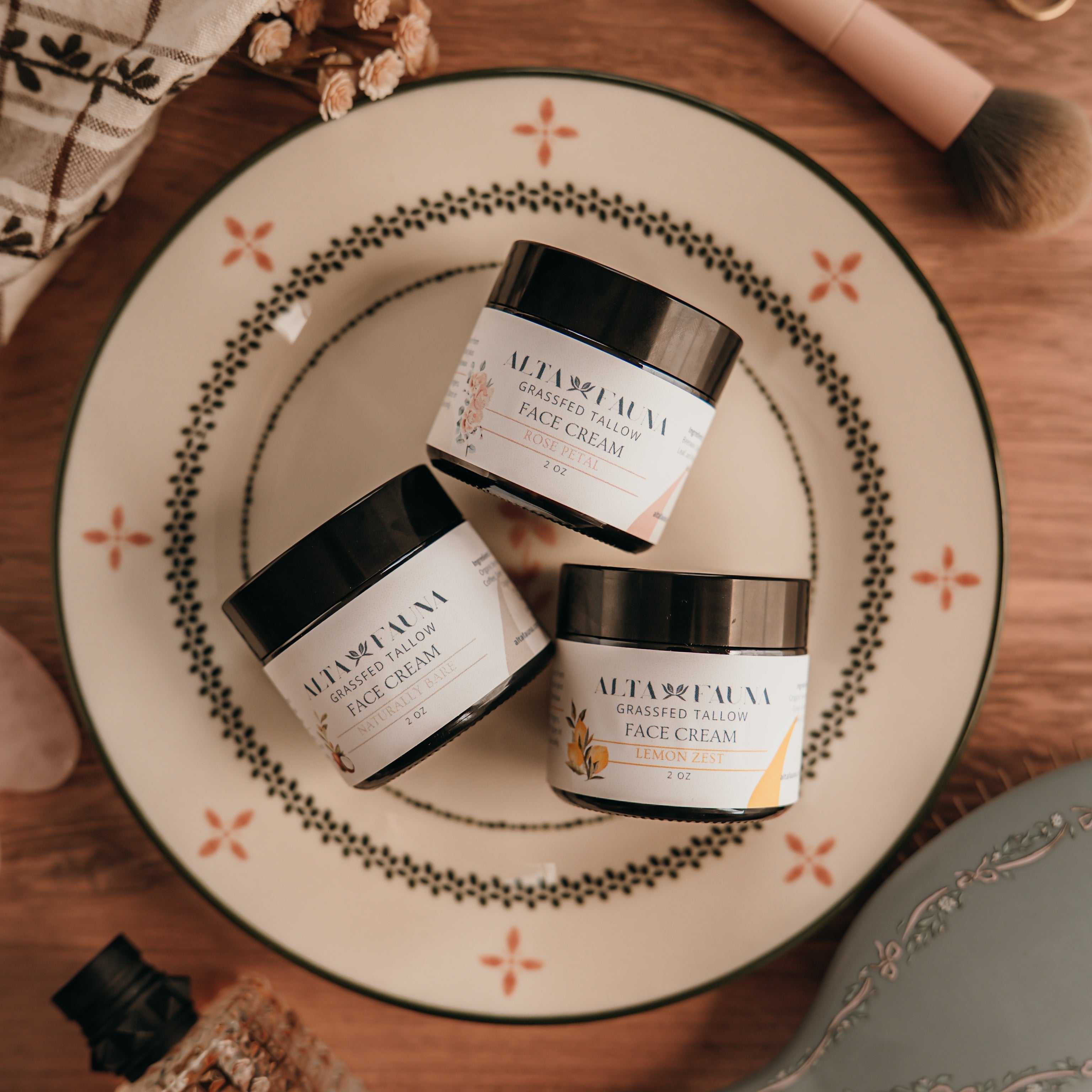 Three jars of Alta Fauna face cream on a decorative plate with a wooden background.