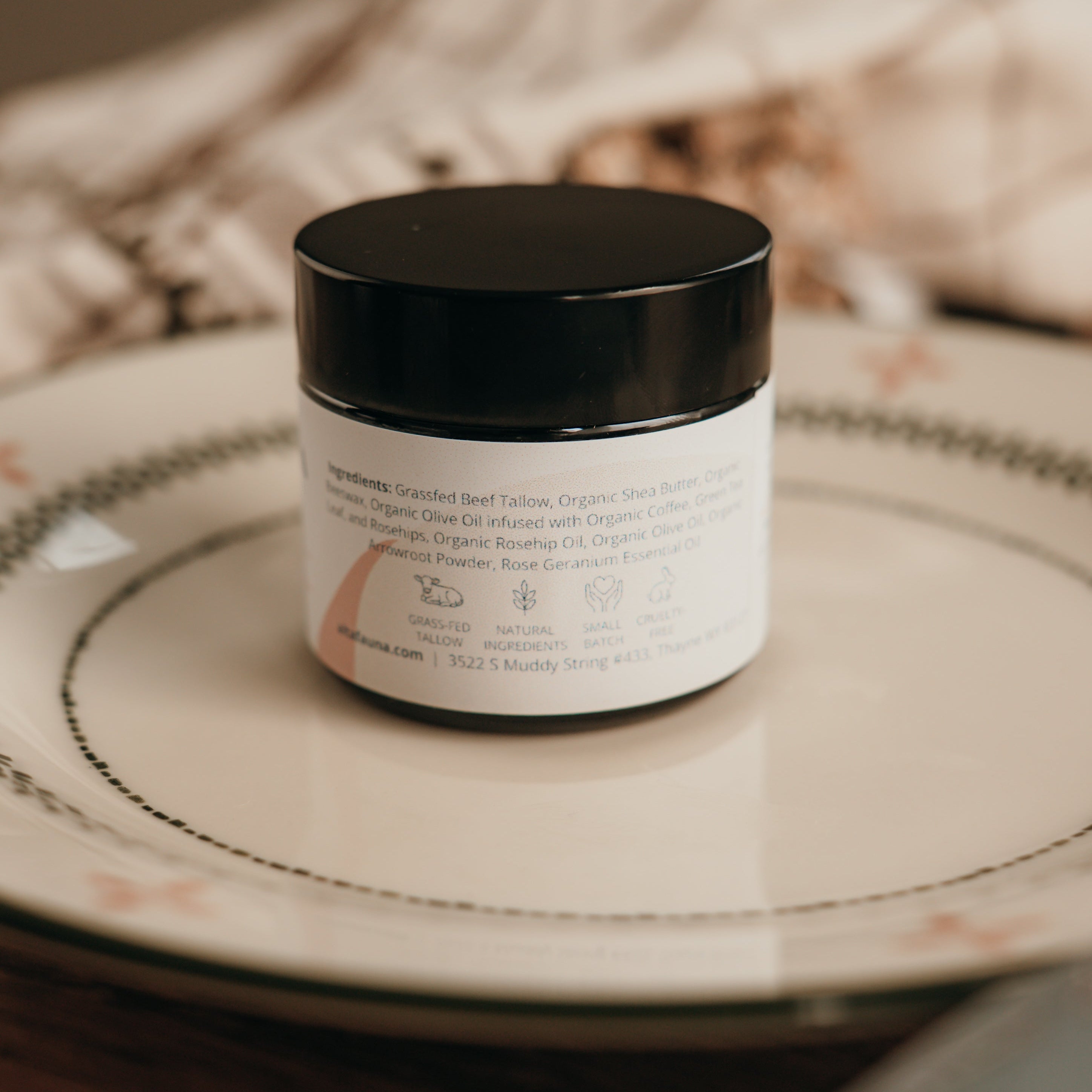 Alta Fauna face cream on a plate with the back of the jar in focus. Shows ingredients, company address and grassfed tallow and natural ingredients. 