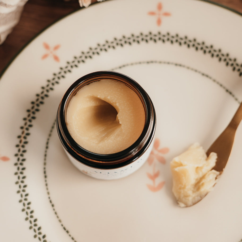 Jar of Alta Fauna face cream on a plate with a spoon. Jar is open and the cream is on a spoon showing the texture.