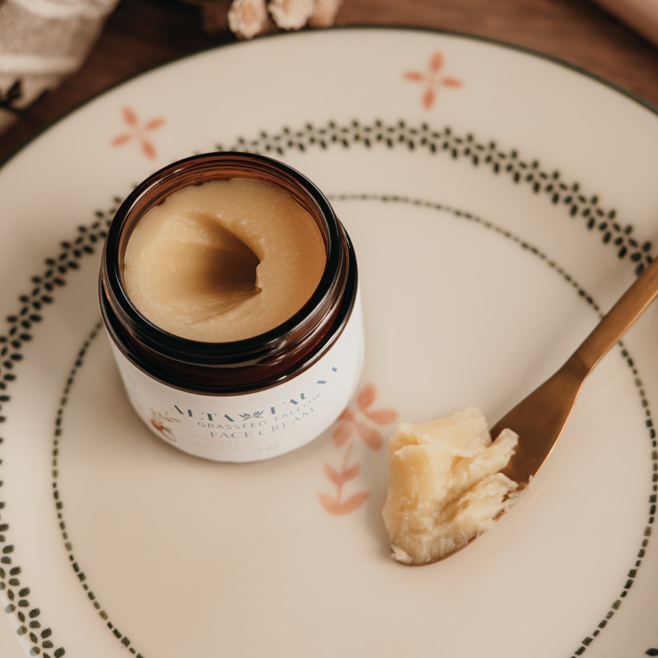 Jar of Alta Fauna face cream on a plate with a spoon. Jar is open and the cream is on a spoon showing the texture.