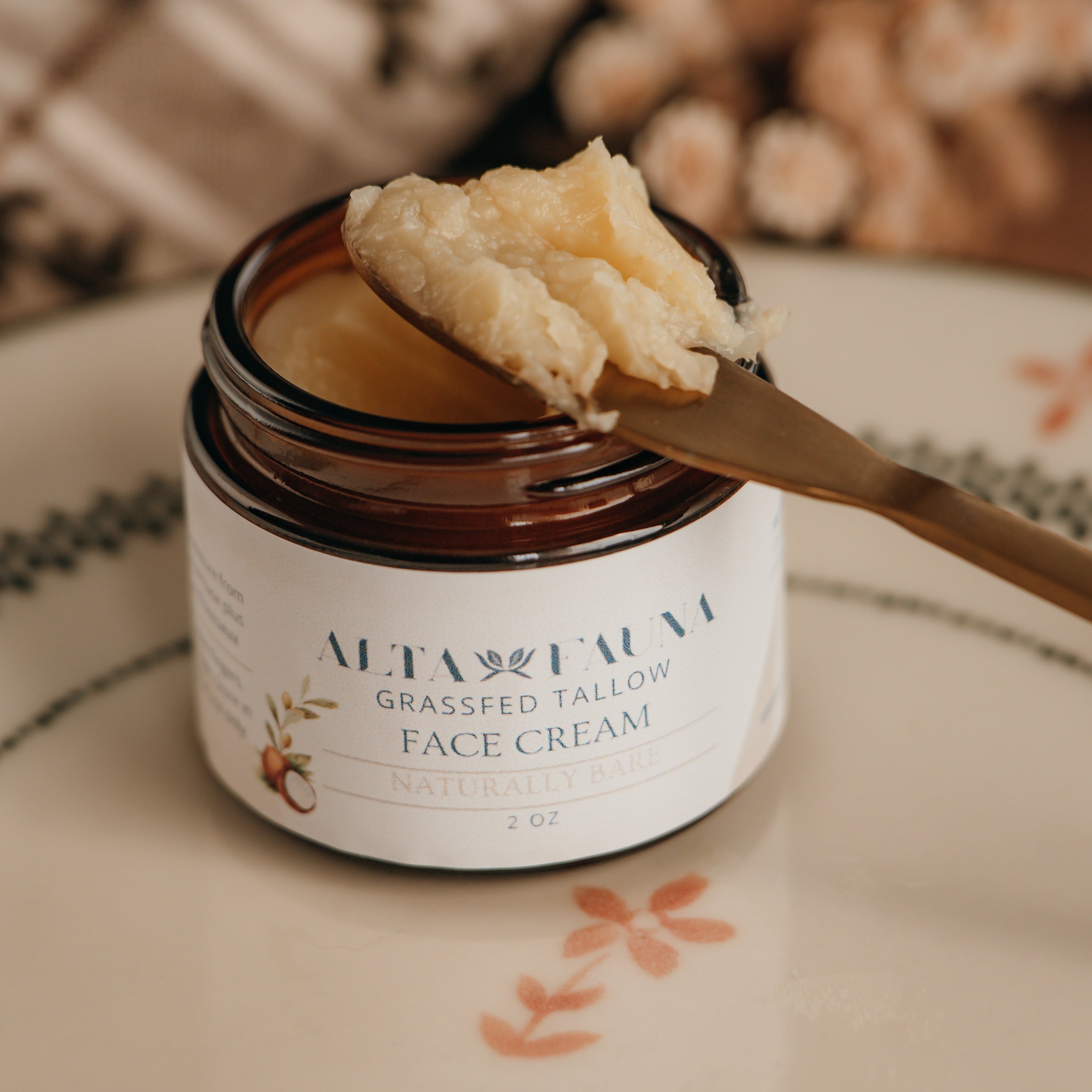 Jar of Alta Fauna face cream on a plate with a spoon. Jar is open and the cream is on a spoon showing the texture. Close up of the label.