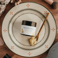 Jar of Alta Fauna face cream on a plate with a spoon. Jar is closed and the cream is on a spoon showing the texture.