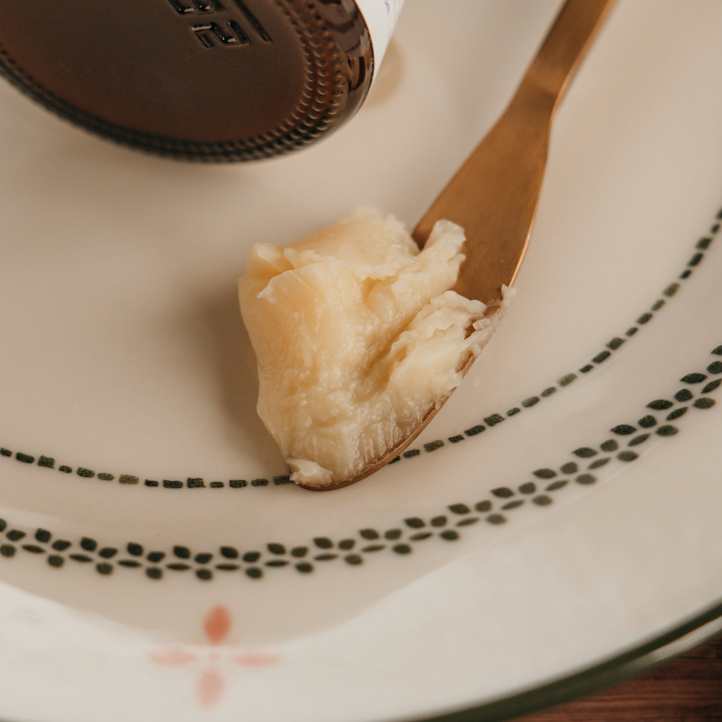 Close-up of a spoon with a scoop of Alta Fauna face cream on a decorative plate.