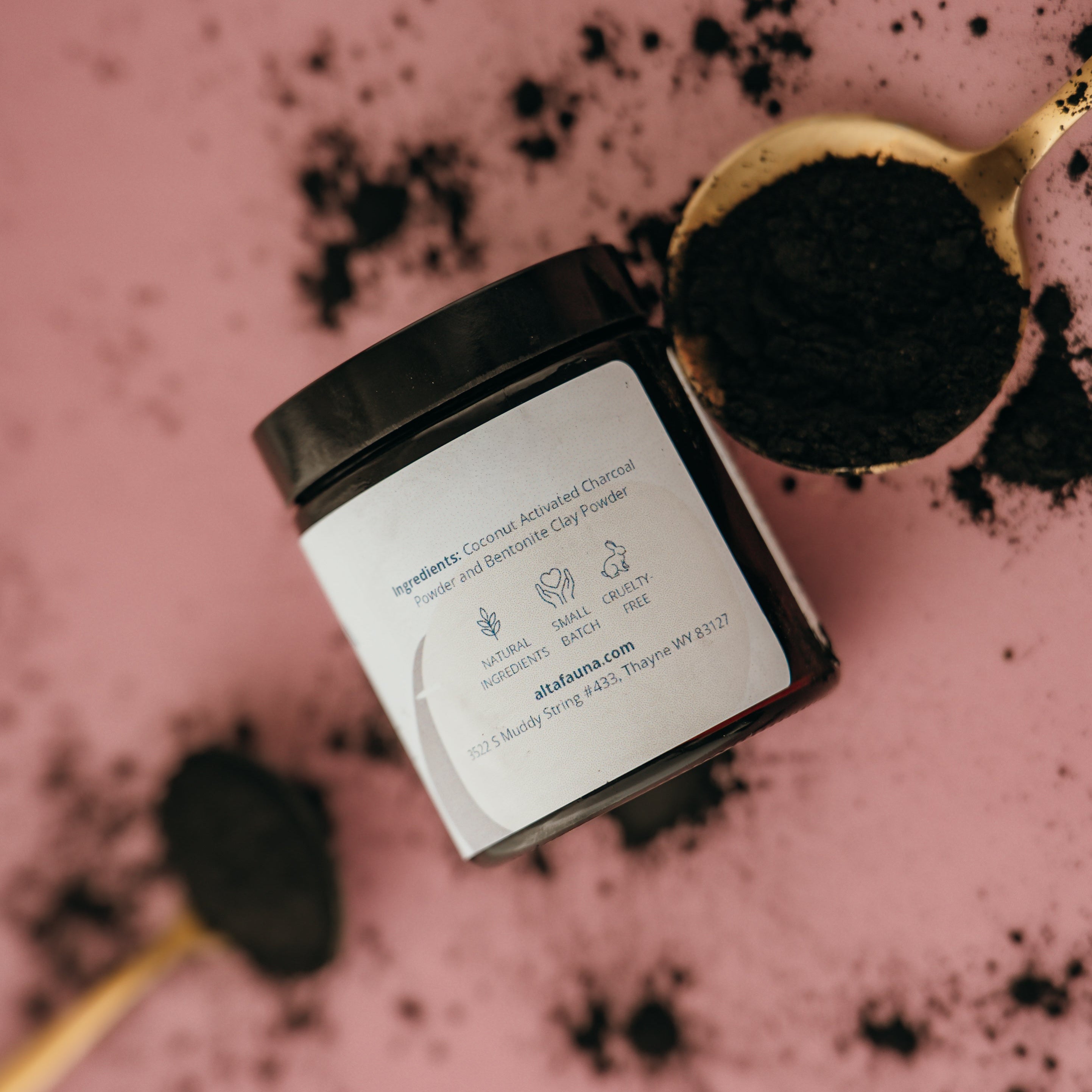 Alta Fauna charcoal and clay face mask with a pink background. Product shown on a spoon on the side. 