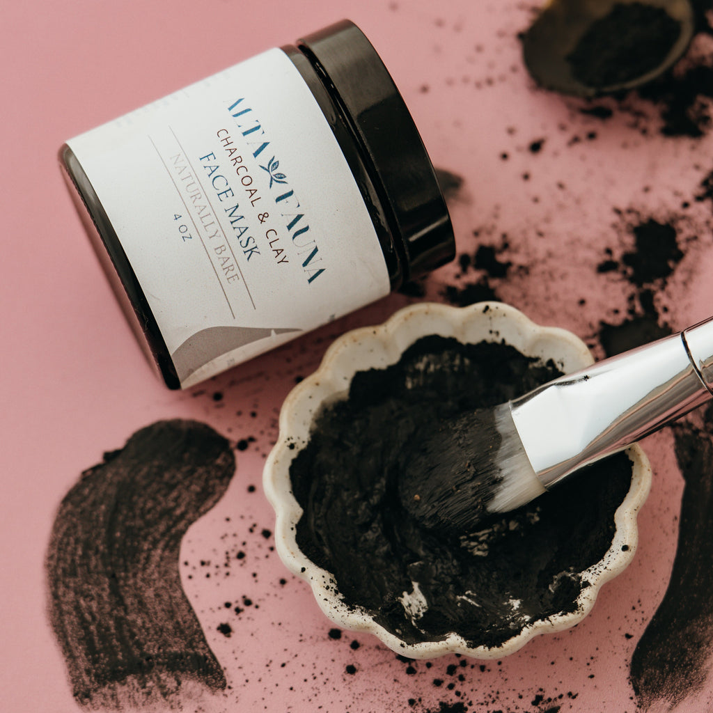 Alta Fauna Charcoal and clay face mask with a brush and wet product on a pink background