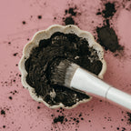 Alta Fauna charcoal and clay face mask with a brush on a pink background