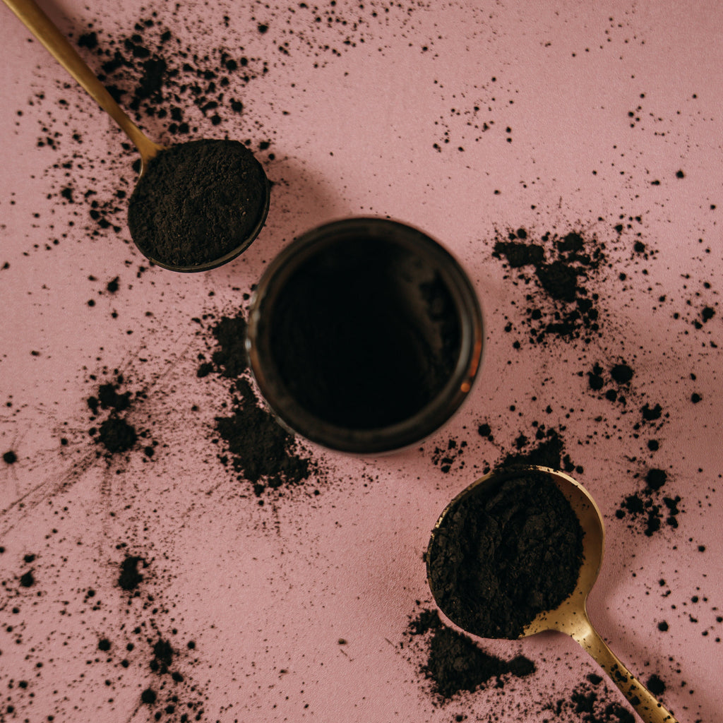 Gold spoons and glass, amber jar with Alta Fauna charcoal and clay face mask powder.