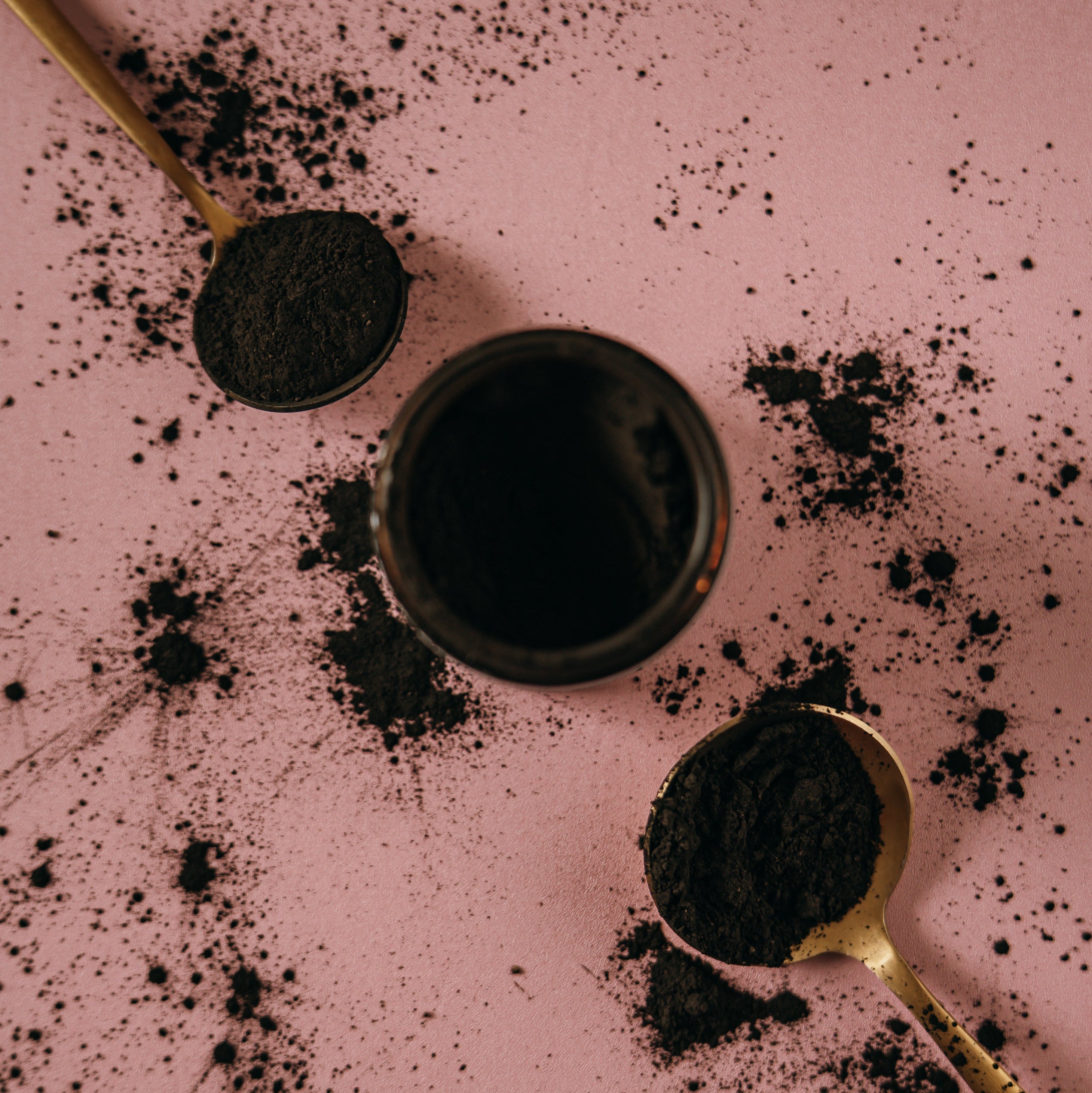 Gold spoons and glass, amber jar with Alta Fauna charcoal and clay face mask powder.