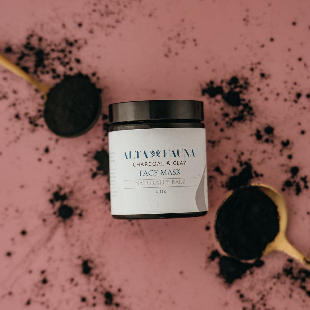 Alta Fauna charcoal and clay face mask jar next to a spoon with black powder on a pink background.