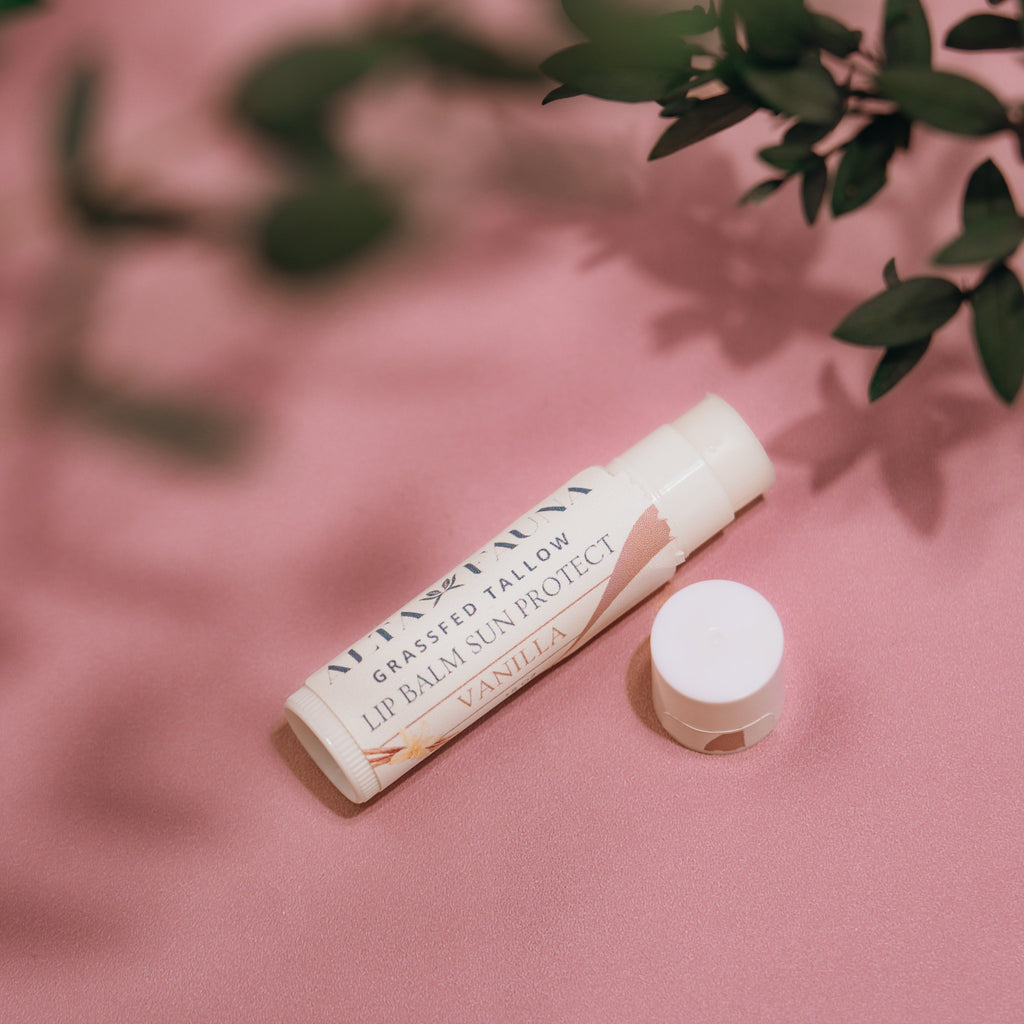 Close‑up of Alta Fauna Grassfed Tallow Lip Balm in Vanilla with mineral zinc for protective daily lip care. Close up of tube and lip balm texture on pink background.