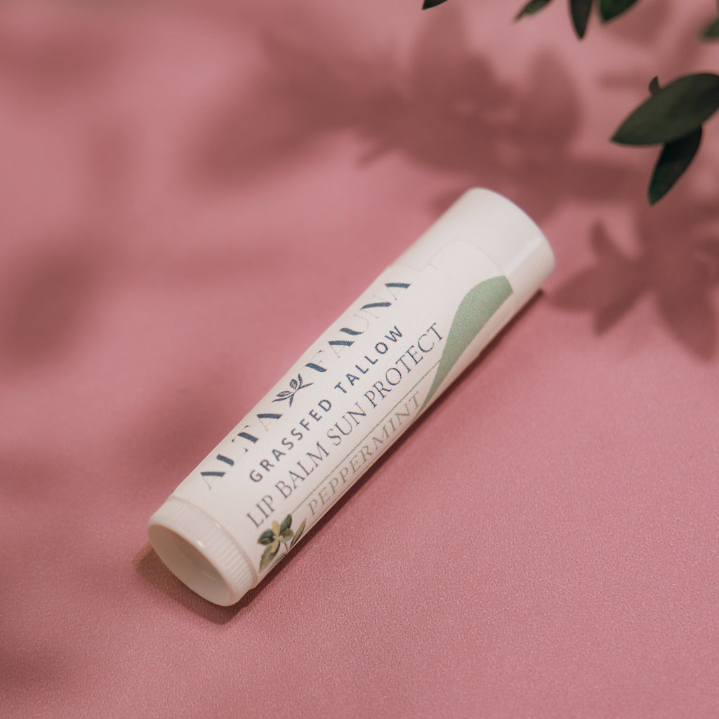 Alta Fauna Peppermint Lip Balm with Sun Protect with lid on a pink background.  Texture of lip balm shown. 