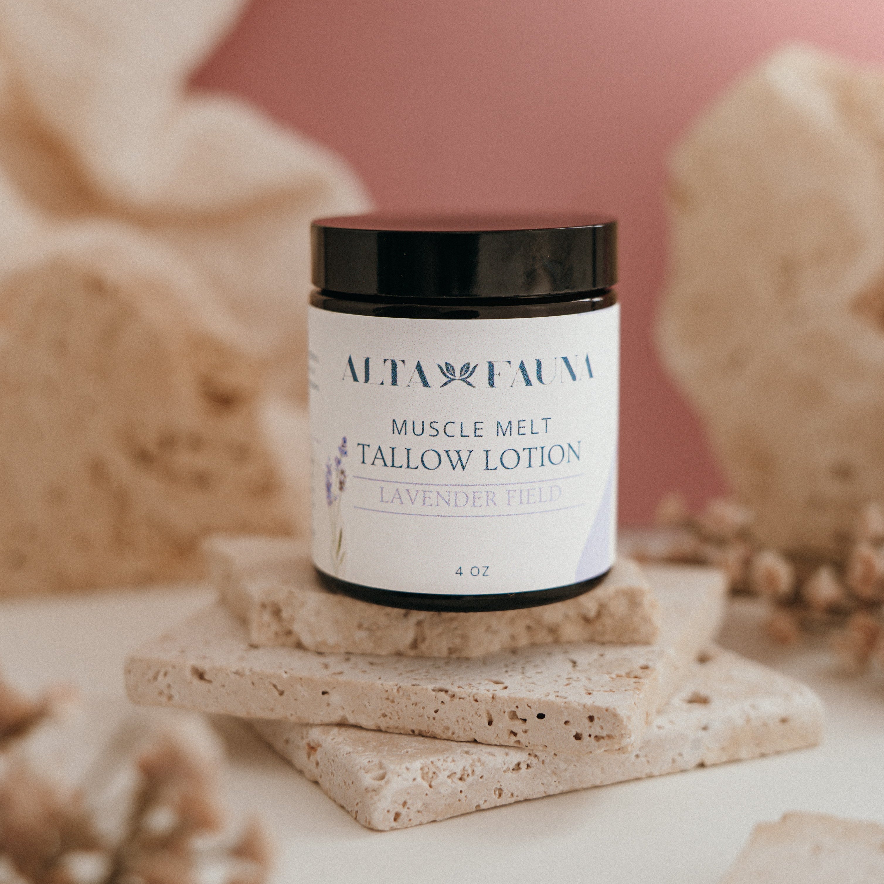 Alta Fauna Muscle Melt Tallow Lotion in Lavender Field (4oz) pictured on a stack of granite with a light pink background.