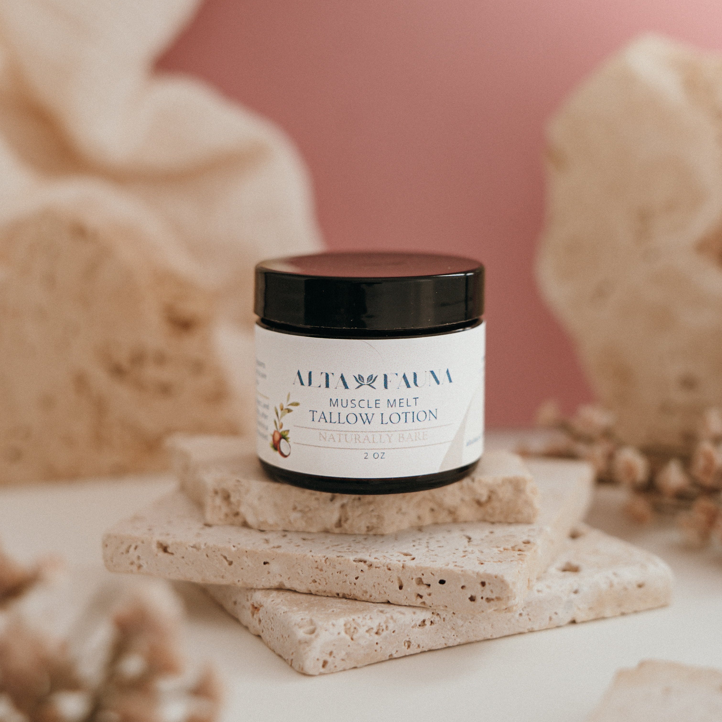 Alta Fauna Muscle Melt Tallow Lotion in Naturally Bare - unscented (2oz) pictured on a stack of granite with a light pink background.