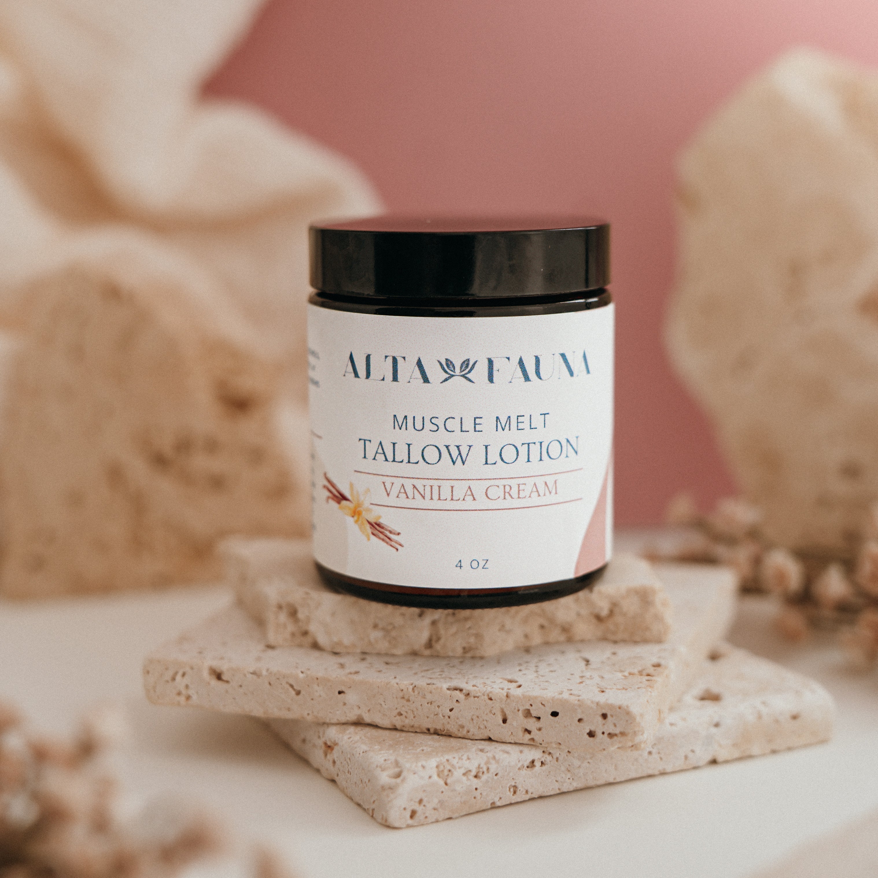Alta Fauna Muscle Melt Tallow Lotion in Vanilla Cream (4oz) pictured on a stack of granite with a light pink background.