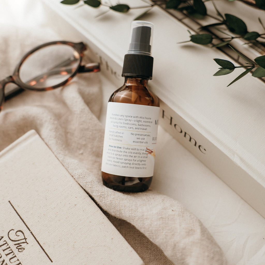 Close‑up of Alta Fauna Room & Linen Spray label showing description and how to use.  Amber, glass spray bottle pictured. 