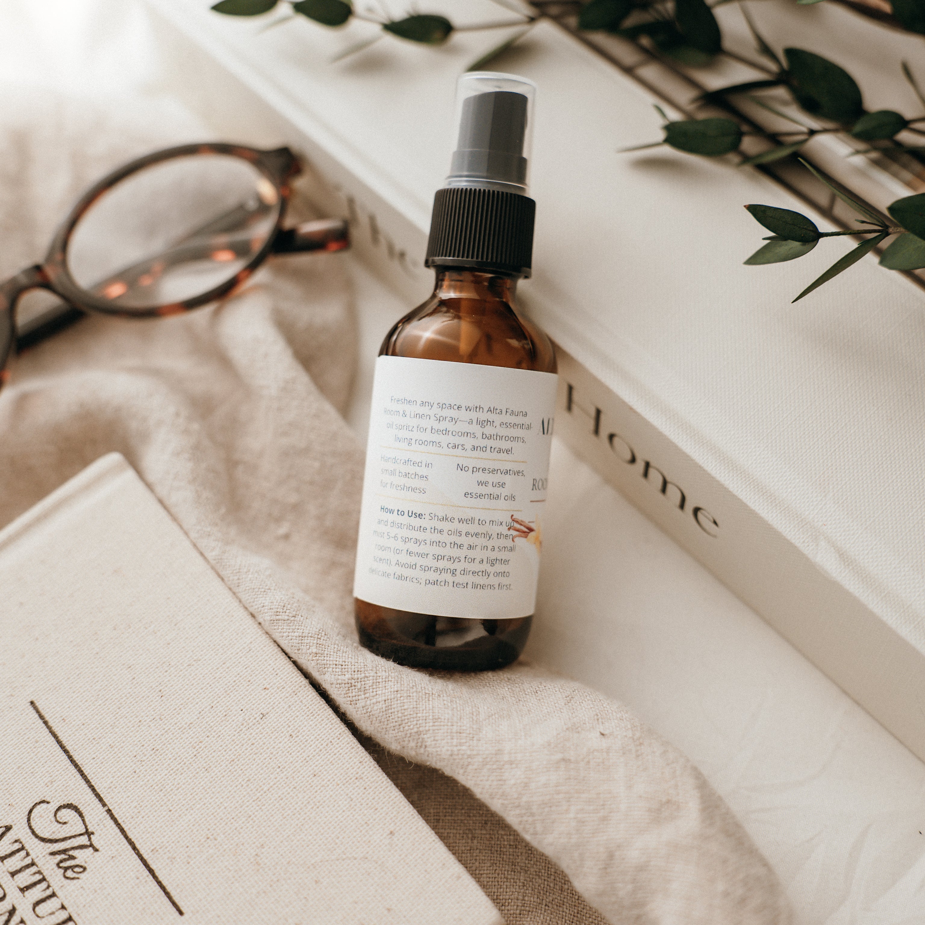 Close‑up of Alta Fauna Room & Linen Spray label showing description and how to use.  Amber, glass spray bottle pictured. 